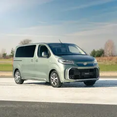 Nowoczesne minivany Toyota Proace Verso w kolorze miętowym stoją na tle krajobrazu.
