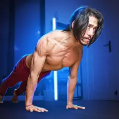 Un homme musclé en position de pompe, pratiquant la musculation poids du corps dans une pièce sombre éclairée par des lumières bleues.