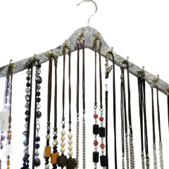 Percha para collares con multitud de cadenas y colgantes de diversos materiales y colores, organizados de forma ordenada.