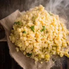 Gorąca kasza bulgur gotowanie na drewnianym stole, parująca i ozdobiona zielonymi ziołami.