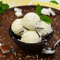 Schüssel mit cremigem Kokoseis, garniert mit Kokosraspeln und Minze. Perfekt, um Kokoseis selber zu machen!