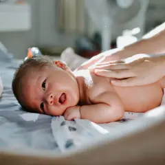 En bebis 1 månad gammal får massage på ryggen.