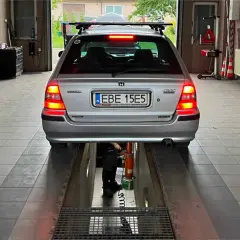 Srebrny Honda Civic na podnośniku w warsztacie. Tablica rejestracyjna EBE 15E5. Może poprzedni właściciel nie przerejestrował auta?