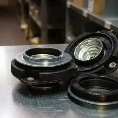 Elementy zawieszenia, w tym łożysko McPhersona, leżą na metalowym blacie.