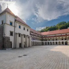 Dziedziniec zamku Sucha Beskidzka z arkadowymi krużgankami i wieżą.
