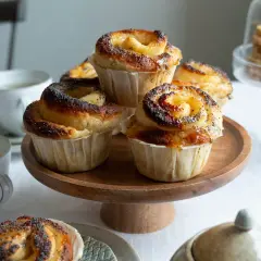 Nybakade bullar med lemoncurd och vallmofrön ligger uppradade på ett träfat. En mysig fika.