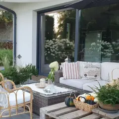Wygodne meble i dekoracje tworzą przytulne miejsce co na taras. Koszyk z dyniami i paproć dodają jesiennego uroku.