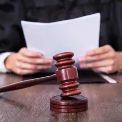 Sędzia w todze czyta dokumenty. Obok młotek sędziowski. Zastanawiasz się, ile czasu ma sąd na dostarczenie wyroku w sprawie karnej?