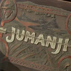 Drewniana skrzynka z napisem "JUMANJI" i reliefami zwierząt, przypominająca rekwizyty z filmów Jumanji.