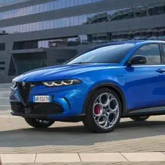 Niebieskie Alfa Romeo Tonale błyszczy na tle nowoczesnego budynku. Sprawdź aktualną alfa romeo tonale cena i odkryj jego możliwości.