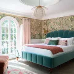 Chinoiserie wallpaper with birds and blossoms offers stunning bedroom wall decor ideas. A teal velvet bed and pink curtains complete the elegant look.