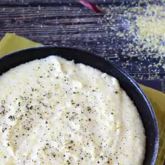 Krämig polenta i gjutjärnspanna, strödd med peppar. Perfekt för ett enkelt polenta recept.