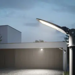 Nowoczesne oświetlenie posesji, zgodne z przepisami, rozświetla podjazd i nowoczesny dom.