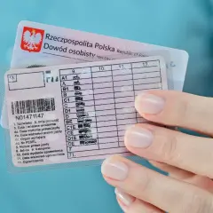 Dłoń trzyma polskie prawo jazdy kategorii B, obok dowodu osobistego.
