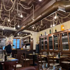 Interno di un ristorante con tavoli apparecchiati e una grande vetrina di vini. Un locale che potrebbe essere tra i migliori ristoranti di Milano per l'atmosfera.