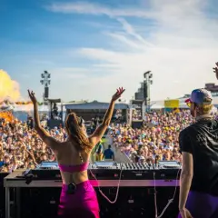 DJ-ka i DJ na scenie, tłum szaleje na festiwalu techno. Wybuchy ognia dodają energii.