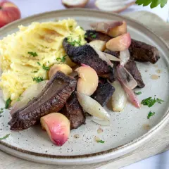Leber braten ohne Mehl: zarte Leberstücke mit karamellisierten Zwiebeln und Pfirsichspalten, serviert mit cremigem Kartoffelpüree und frischer Petersilie.