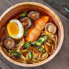 Eine Schüssel Ramen mit Ei, Pilzen und Chili. Der würzige Sud weckt die umami zunge und verspricht ein intensives Geschmackserlebnis.