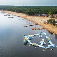 Sielpia atrakcje: dmuchany plac zabaw na wodzie, plaża z ludźmi, wypożyczalnia sprzętu wodnego i las.