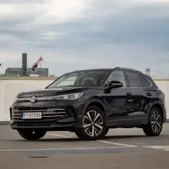 Czarny VW Tiguan Allspace na parkingu pod chmurką. Elegancki SUV z chromowanymi detalami i nowoczesnymi felgami.