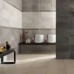 Bagno moderno con lavabi sospesi e piastrelle a diverse altezze, che creano un effetto visivo dinamico.