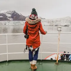 Podróżniczka podziwia lodowce na archipelagu Svalbard. W oddali widać góry i morze.