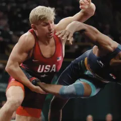 Två brottare i intensiv kamp. En bär USA:s färger, den andra en mörkblå dräkt. Spänningen är påtaglig i denna wrestling sverige-match.