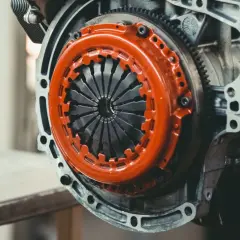 Mechanizm sprzęgła z pomarańczową osłoną. Zastanawiasz się, ile kosztuje wymiana dwumasy?