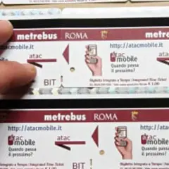 Dita sfiorano un biglietto metro Roma da 2 euro, con logo Atac e indicazioni per l'acquisto online.