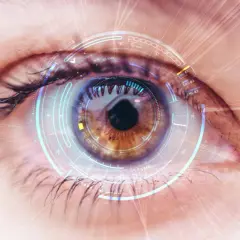 Zbliżenie oka z futurystycznym interfejsem, sugerującym zaawansowaną diagnostykę, np. w kierunku angiopatii.