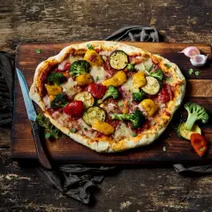 Eine köstliche vegane Pizza mit buntem Gemüse-Belag: Brokkoli, Zucchini, Paprika und Tomaten.