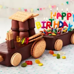 Schokoladen-Traktor-Torte, die man leicht selber machen kann, mit bunten Kerzen und Gummibärchen verziert.