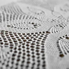 Dettaglio di un centrino all'uncinetto bianco, con motivi floreali e traforati. Un tocco di eleganza che dimostra come si usano ancora i centrini sui mobili.