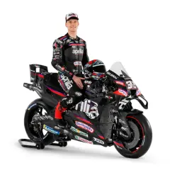 Piloto de Aprilia MotoGP posa junto a su moto de carreras negra y roja, listo para la acción.