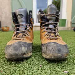 Bottes de randonnée usées, prêtes à être ressemelées. Elles ont vu du terrain et méritent une seconde vie.