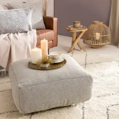 Gemütliches Wohnzimmer im hygge stil mit Ledersofa, Kissen, Decken, Kerzen und einem Teppich.
