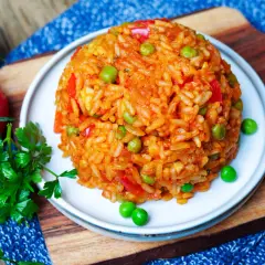 Ein Berg aus aromatischem Djuvec Reis mit Erbsen und Paprika, garniert mit frischer Petersilie und Tomaten.