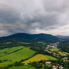 Góry stołowe, z ich płaskimi szczytami, tworzą malowniczy krajobraz z zielonymi polami i lasami, a w oddali widać miasteczko.