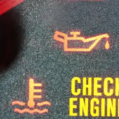 Czerwona kontrolka oleju świeci się, sygnalizując problem. Obok widać ikonę termometru i napis "CHECK ENGINE".
