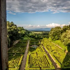 Giardini all'italiana del Castello Ruspoli, con siepi geometriche, fontana centrale e vista panoramica sulla campagna.