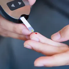 Osoba mierzy poziom glukozy glukometrem. Zrozumienie, dlaczego cukier rośnie bez jedzenia, jest kluczowe dla diabetyków.