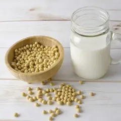Bol en bois rempli de graines de soja, à côté d'un verre de lait de soja. La lécithine de soja est un ingrédient clé.