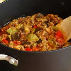 Une poêle remplie de ratatouille, comme dans le film, avec des légumes colorés et une cuillère en bois.
