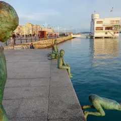 Los raqueros, esculturas de bronce, observan el mar desde el paseo marítimo. Uno se lanza al agua, otro espera sentado.
