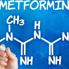 Struktura metforminy i jej potencjalne metformina skutki uboczne. Ręka z markerem pisze wzór chemiczny na niebieskim tle.