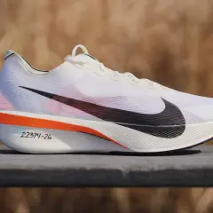 Białe buty treningowo startowe Nike z czarnym logo. Pomarańczowe akcenty i numeracja na podeszwie.