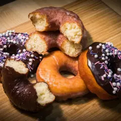 Deliciosos donuts caseros, algunos cubiertos de chocolate y chispas, otros glaseados, listos para disfrutar.