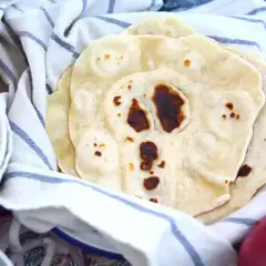 Färska tortillabröd, perfekta för ditt nästa tortilla recept. Bredvid syns skålar med tillbehör som ost och lök.