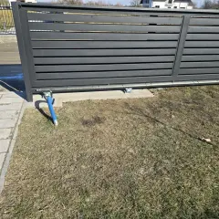 Widoczny mechanizm bramy przesuwnej, z wózkami podtrzymującymi. Jaki rozstaw wózków do bramy przesuwnej jest kluczowy dla płynnego działania.