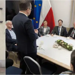 Biuro poselskie Michała Kowalskiego. Spotkanie przy stole z flagami Polski i UE.